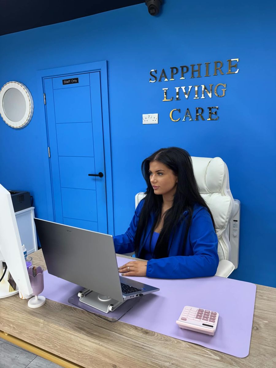 A member of the Sapphire Living Care team working in the office in front of the Sapphire Living Care sign